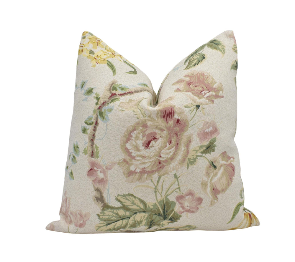 A decorative pillow with a floral print design, featuring various shades of pink and green flowers and leaves.