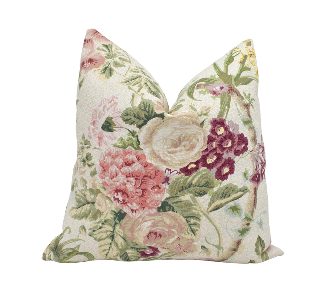 A decorative pillow with a floral print featuring pink, white, and purple flowers and leaves.