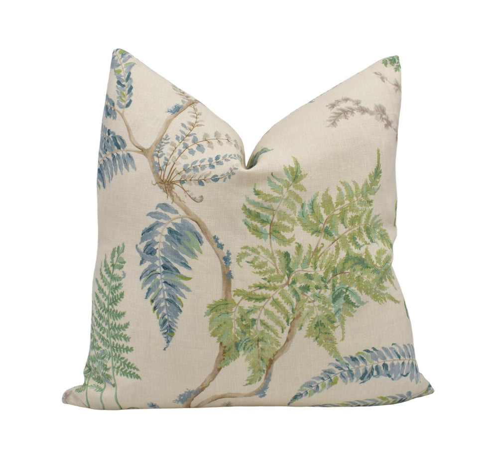 a decorative pillow with a leafy pattern in shades of green and blue.