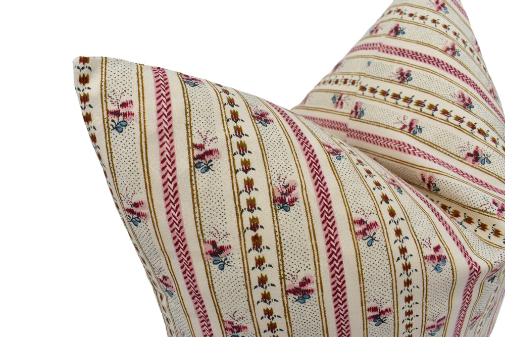 A close-up image of a decorative pillow with a floral pattern in shades of pink, white, and red.