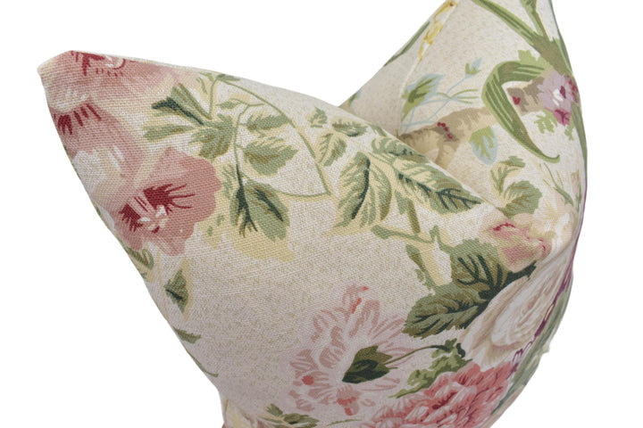 A close-up image of a floral print pillow with a mix of pink, green, and white colors.