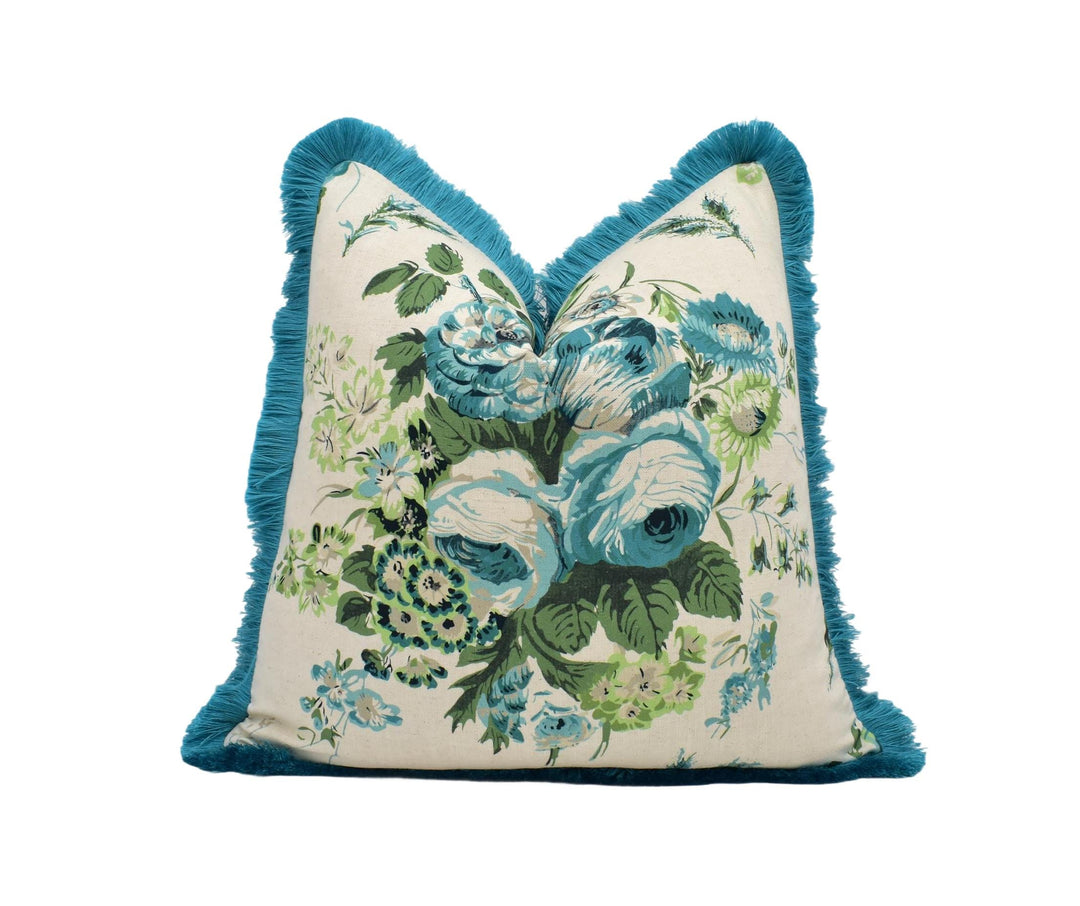 A decorative throw pillow with a floral print and a blue fringe border.
