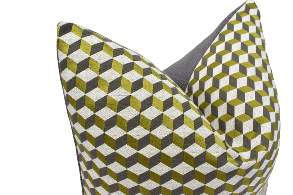 a close-up view of a decorative pillow with a geometric pattern of green and gray cubes.