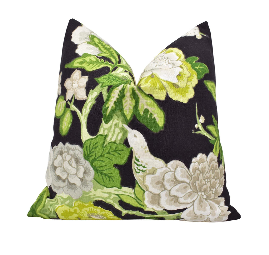 a black pillow with white and green flowers on it