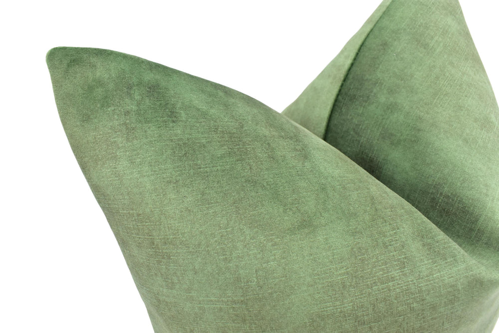 A close-up view of a green, textured fabric, possibly a pillow or cushion, with a slightly curved shape.