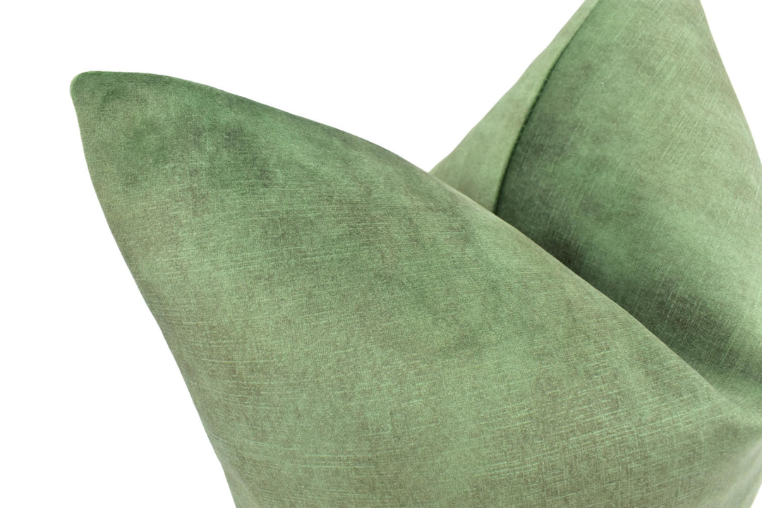 A close-up view of a green, textured fabric, possibly a pillow or cushion, with a slightly curved shape.