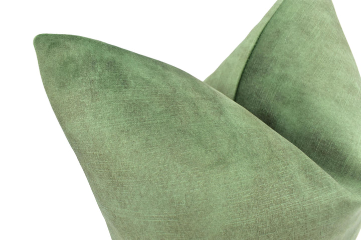 A close-up view of a green, textured fabric, possibly a pillow or cushion, with a slightly curved shape.