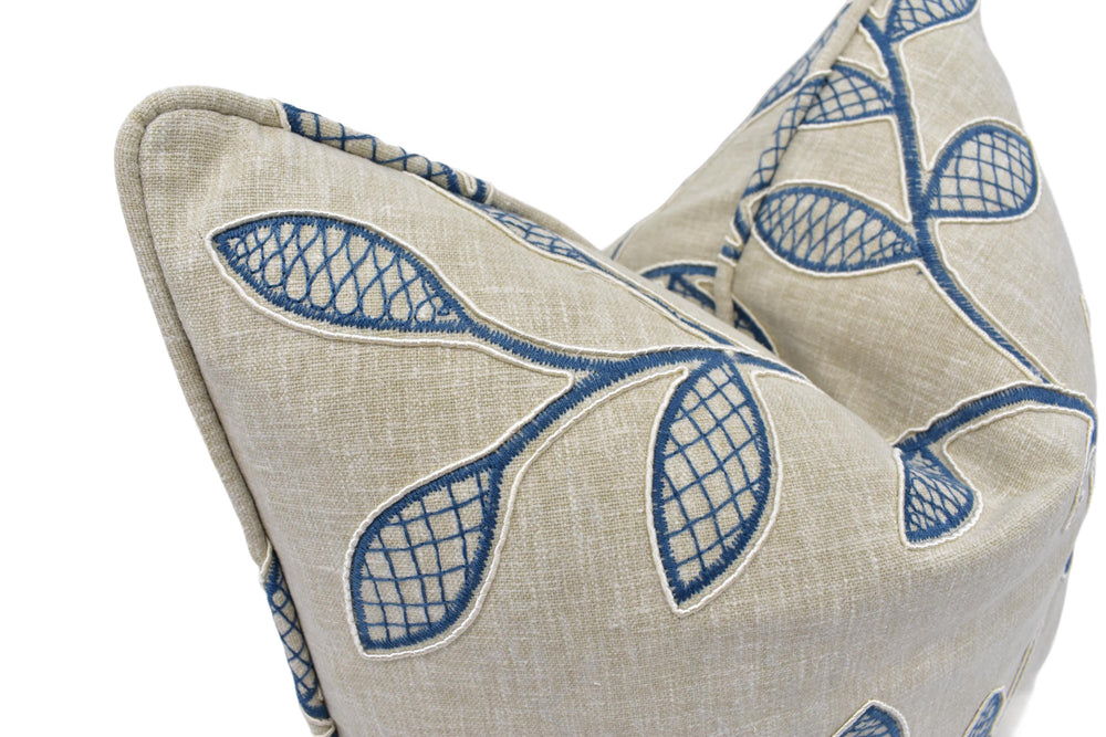 a close-up view of a beige fabric with blue leaf patterns, which appears to be a decorative pillow or cushion.