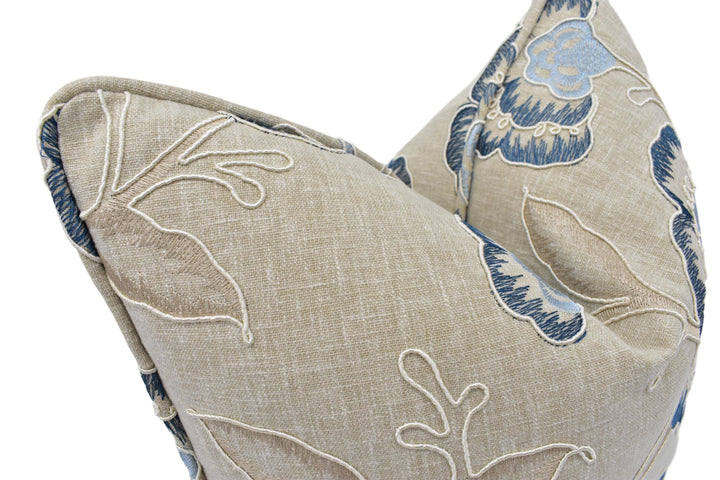 a close-up view of a beige fabric with blue floral embroidery.