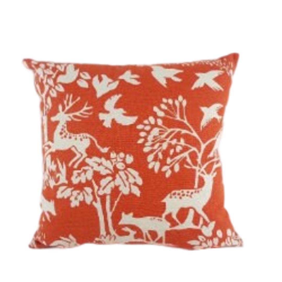 a red and white pillow with deer and trees on it