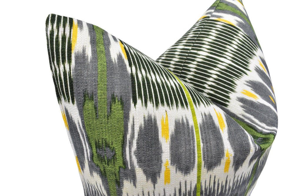 a close-up view of a decorative pillow with a vibrant, colorful pattern featuring green, gray, and yellow stripes and shapes.