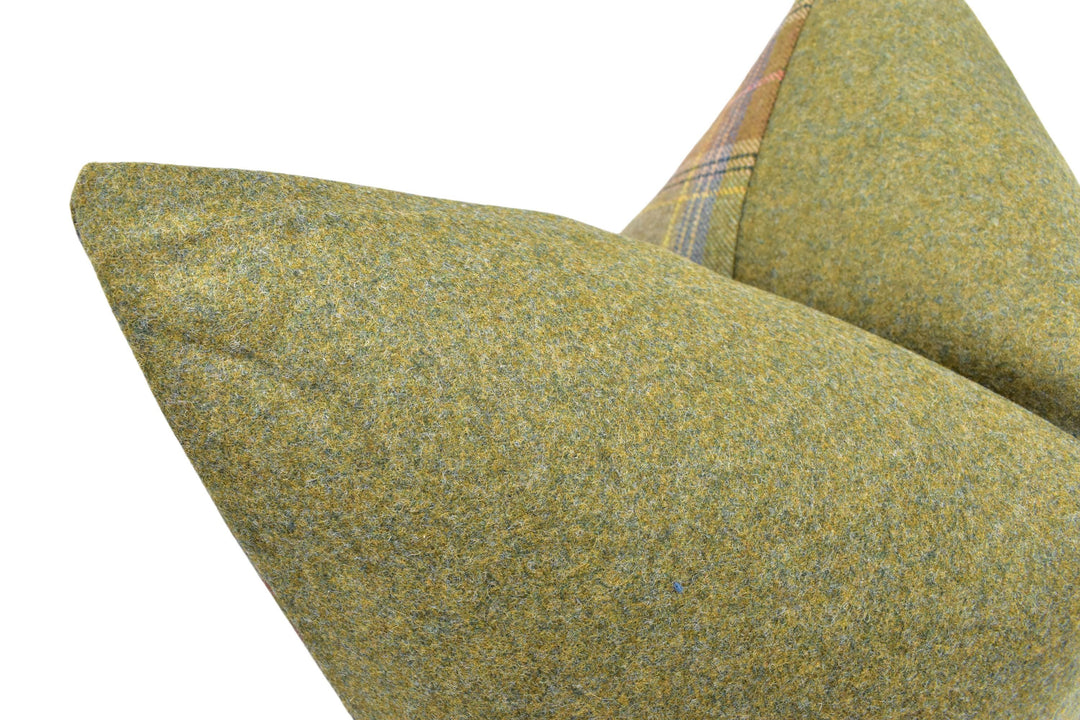 A close-up view of a green, textured fabric, possibly a pillow or cushion, with a patterned fabric visible on the right side.