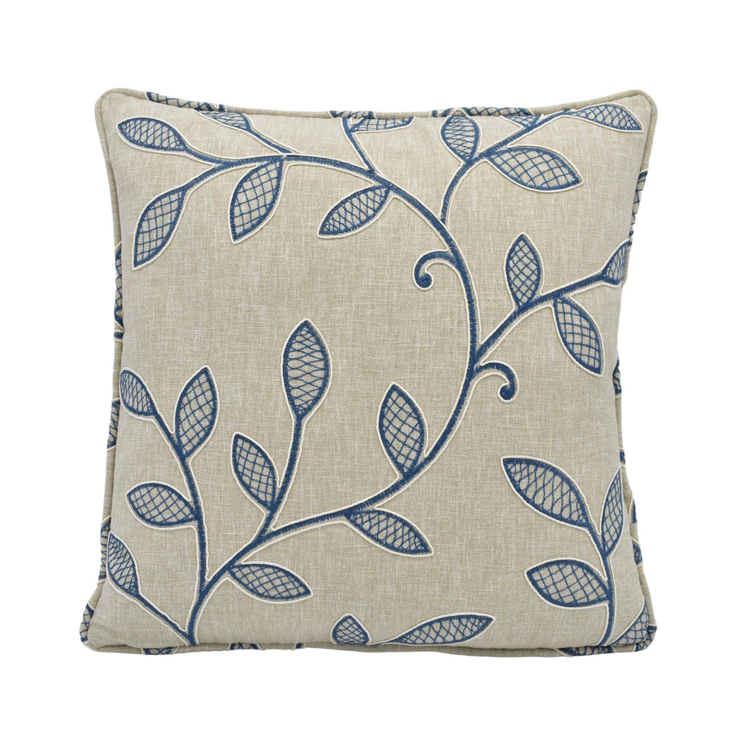 a square pillow with a beige background and a blue leaf pattern.