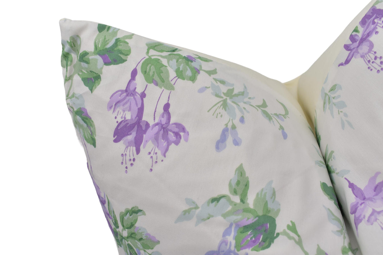 a white pillow with purple and green flowers on it