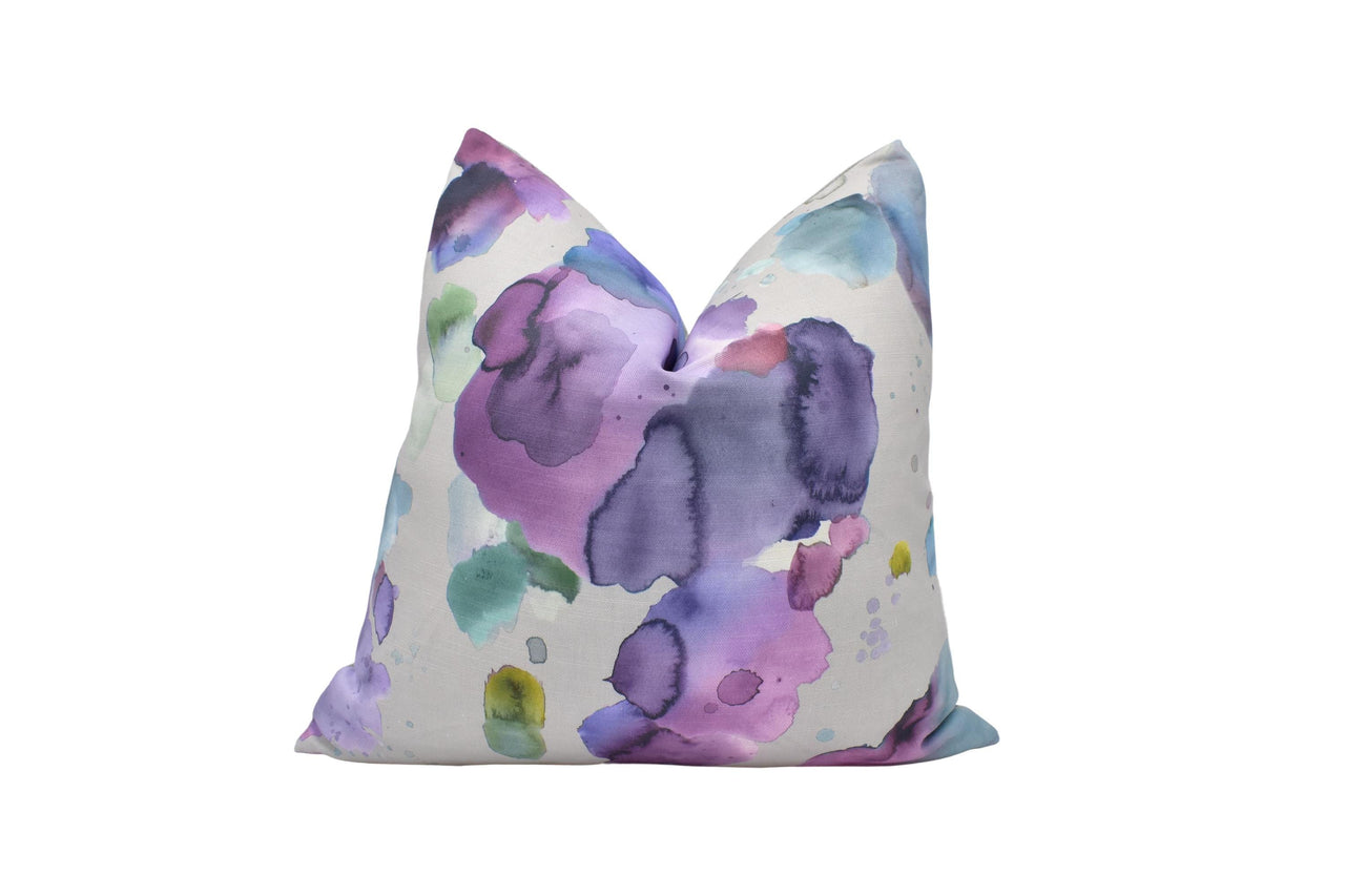 a purple and green pillow on a white background